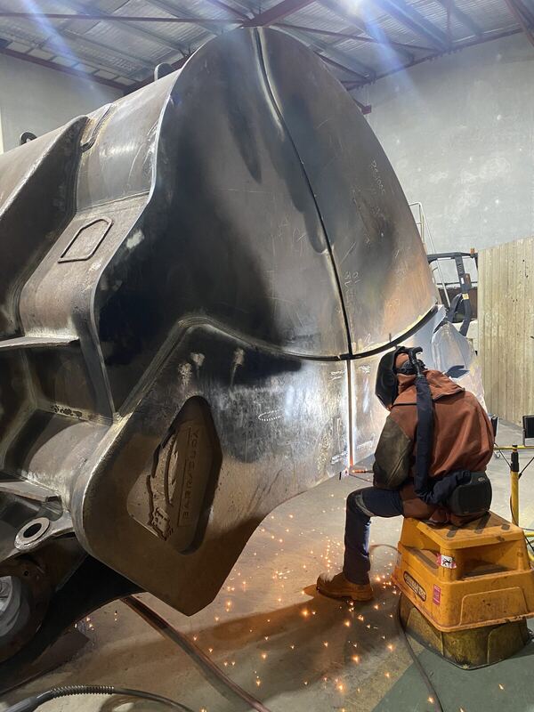 Welder repairing a heavy steel bucket shell, sparks flying